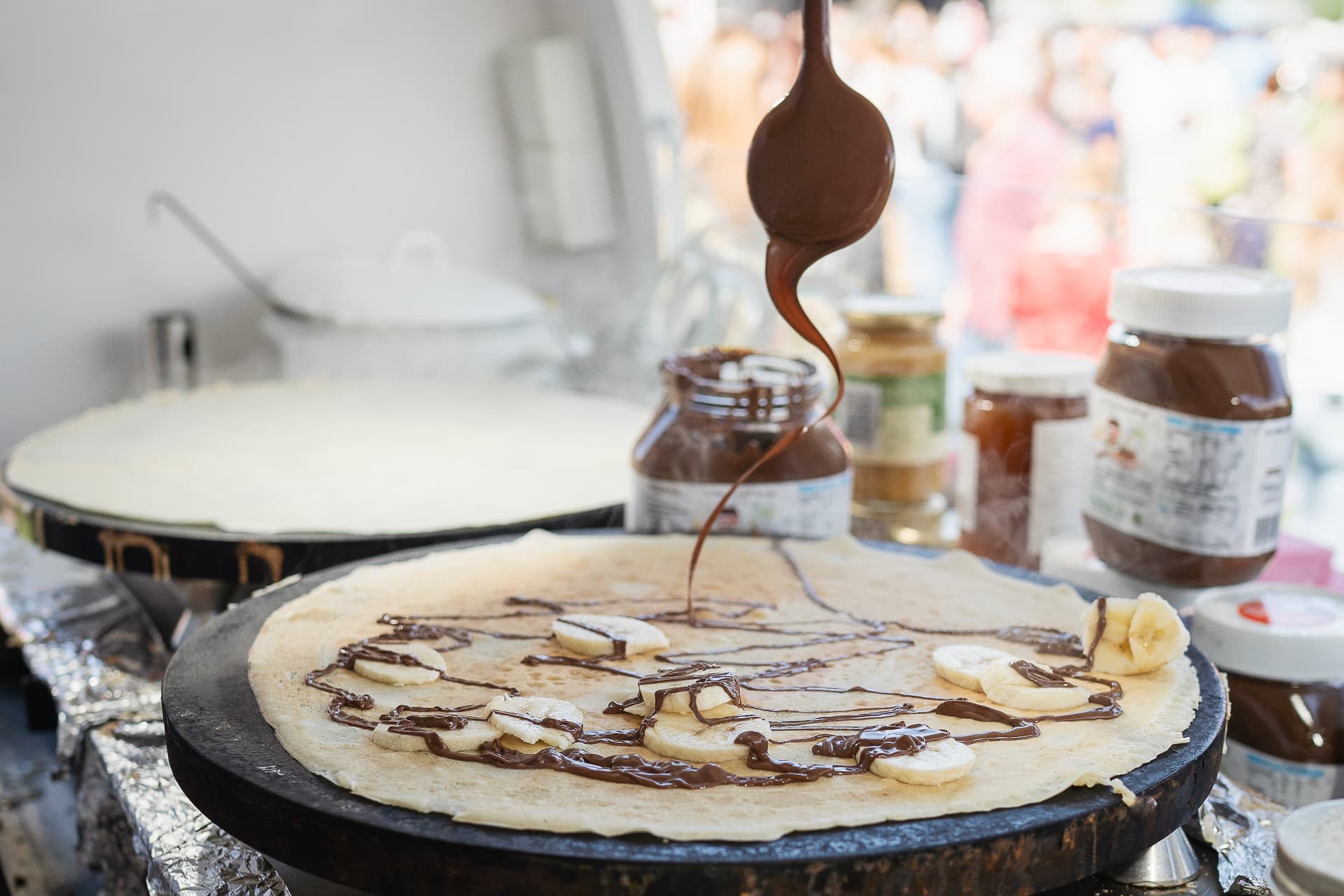 Frisch gebackener Crêpe mit Banane und Schokolade auf der Crêpe-Platte