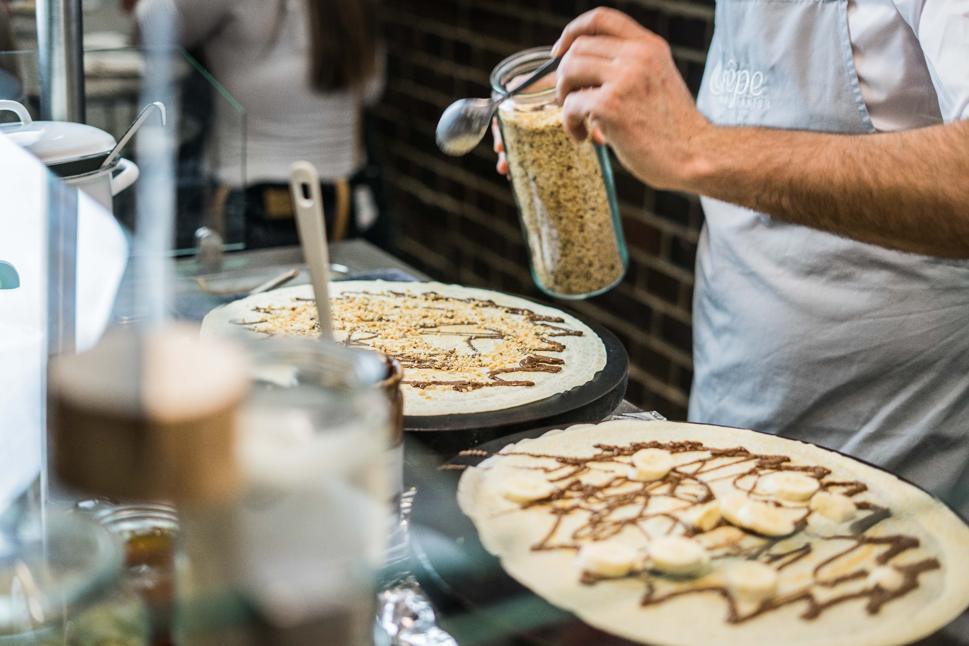 Zwei Crêpes mit Banane, Schokolade und Haselnüssen frisch auf den Crêpe-Platten