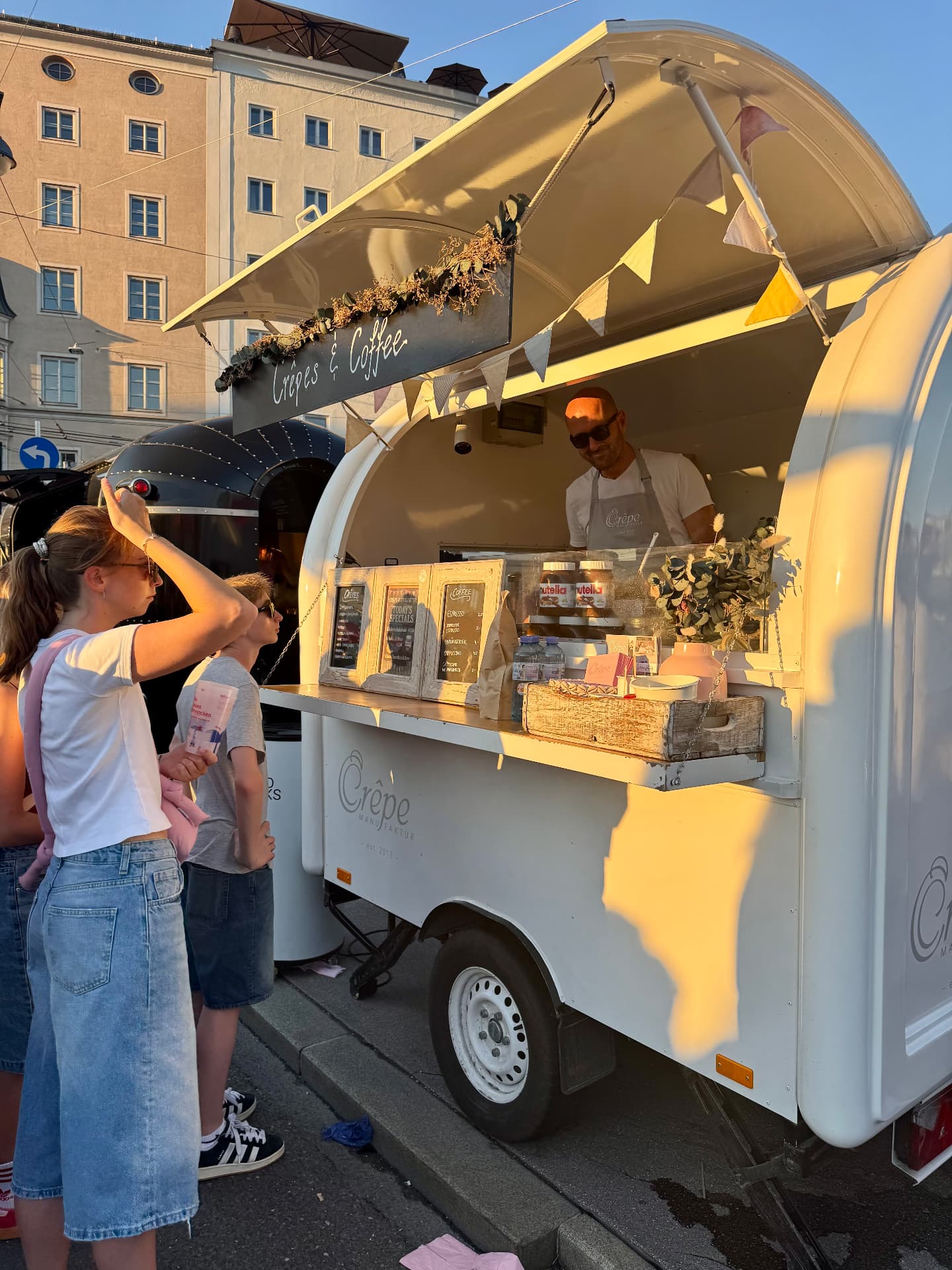Crêpe-Trailer in der Salzburger Altstadt in der Abendsonne mit wartenden Gästen